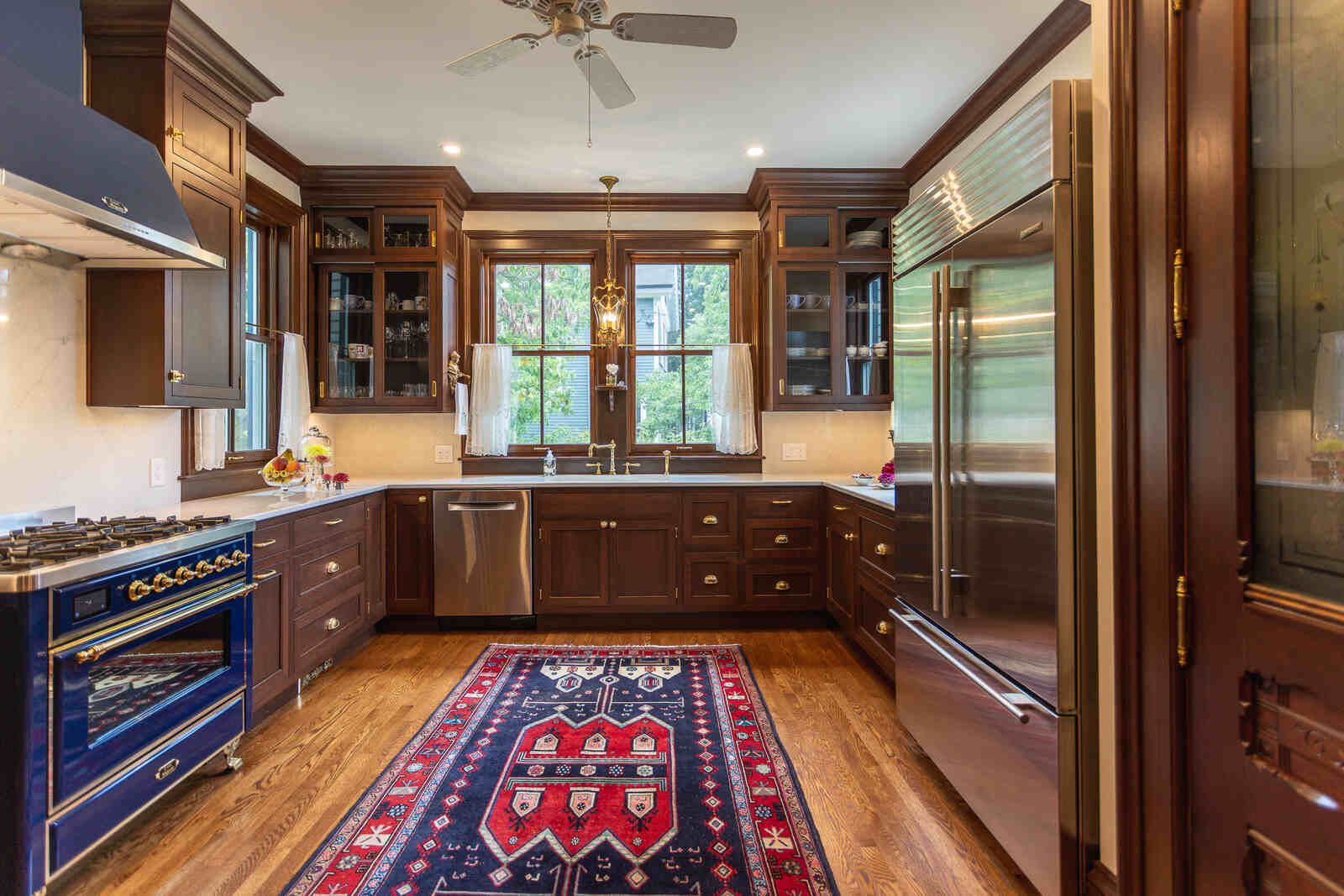 mahogeny cabinets with dark blue professional stove and range hood kitchen with glass cabinets